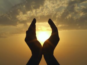 hands holding the sun at dawn